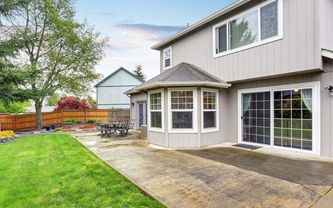 Nice home with a large backyard with a tree.